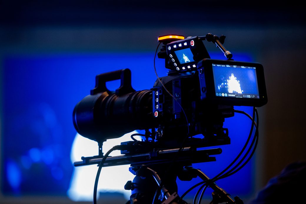 A cinema camera on set under blue stage lighting