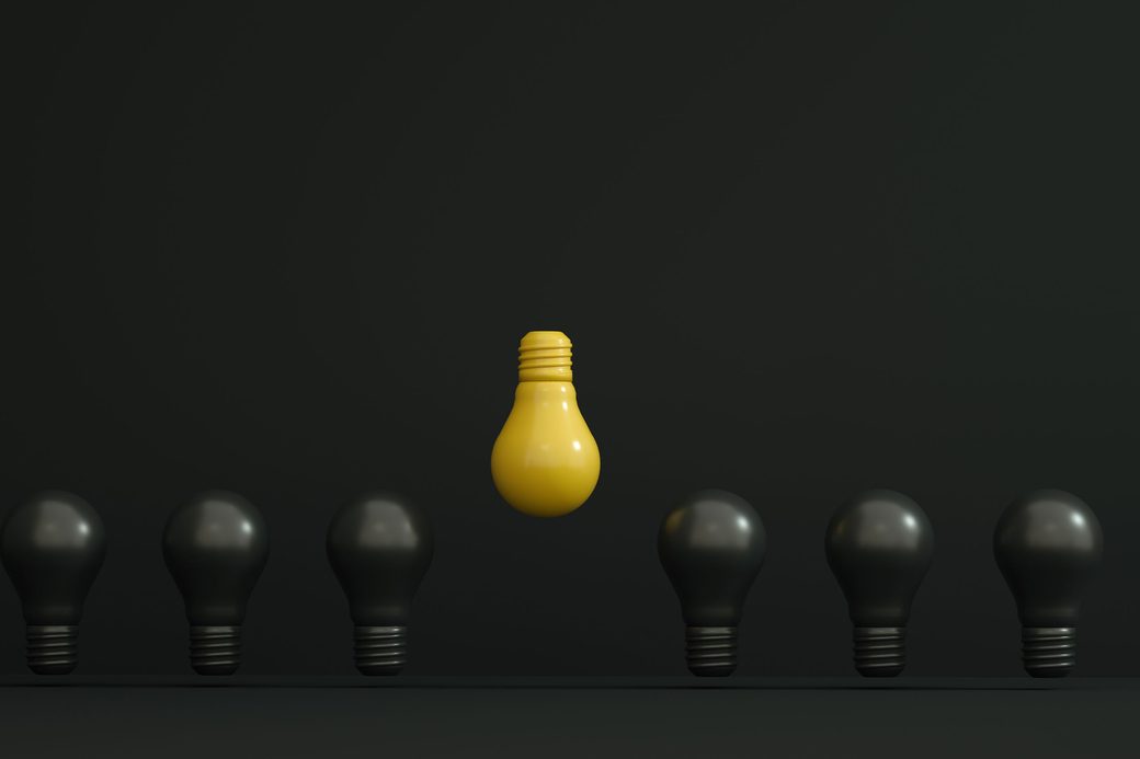 A single yellow lightbulb raised above a row of dark bulbs