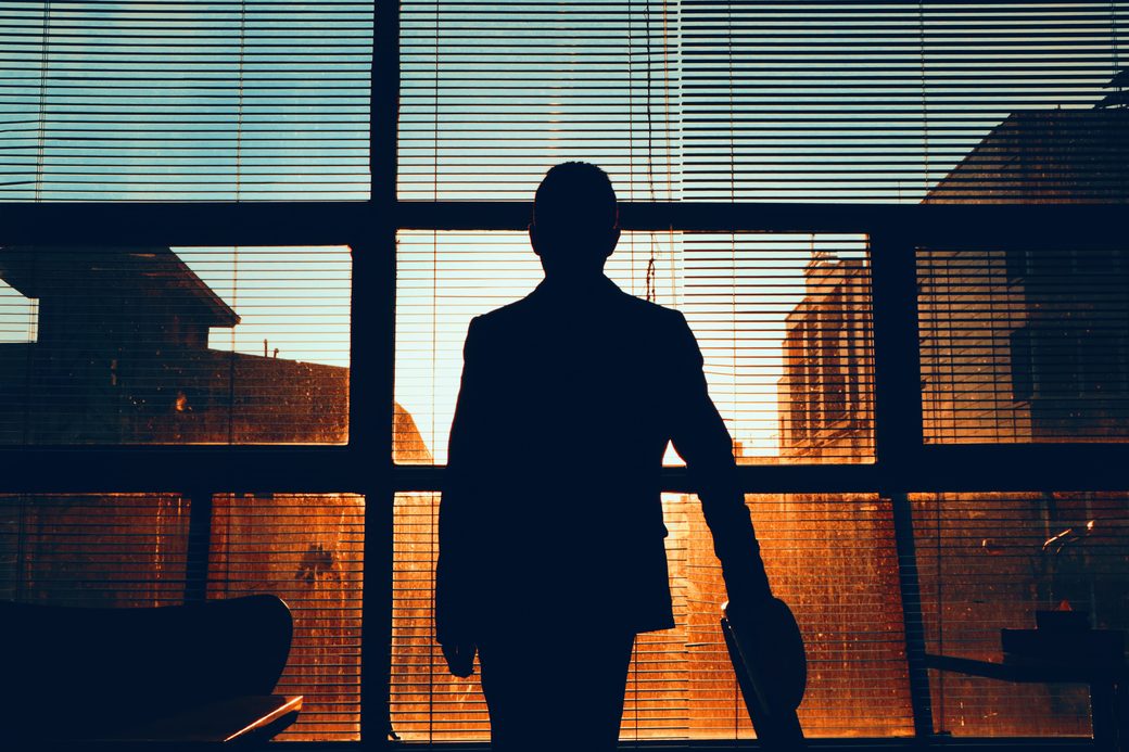 Silhouette of a businessperson at an office window at sunset
